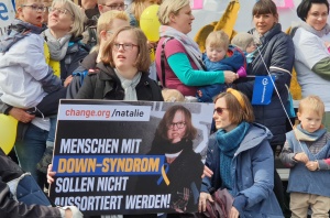 Die Down-Syndrom-Aktivistin Natalie Dedreux mit ihrem Plakat "Menschen mit Down-Syndrom sollen nicht aussortiert werden".