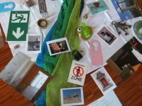 Geschwisterseminartag 2019: auf dem Boden ausgebreitete Gegenstände wie eine Collage, z.B. ein Notausgangsschild, Fotos, Schlüssel, zwei grüne Tücher